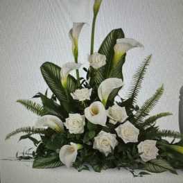 White calla lilies and roses arranged with dark greenery