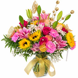 Bright mixed bouquet in a glass vase with a gold ribbon