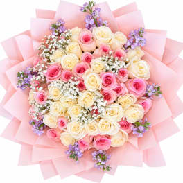 Bouquet of pink and cream roses with purple accents wrapped in pink paper