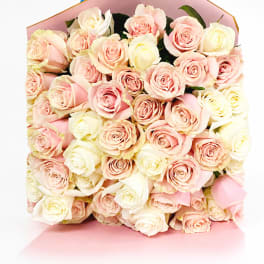 Bouquet of pale pink and cream roses wrapped in pink paper