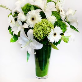 White lilies and gerbera daisies in a green glass vase