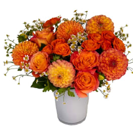 Orange and peach flower arrangement in a white vase