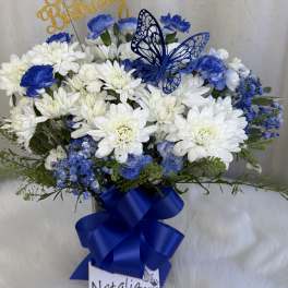 Blue and white flower arrangement with a butterfly topper and ribbon