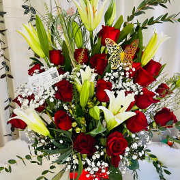 Red roses and white lilies in a basket with baby's breath