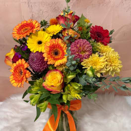 Bright mixed bouquet with gerbera daisies, roses, and dahlias in a glass vase