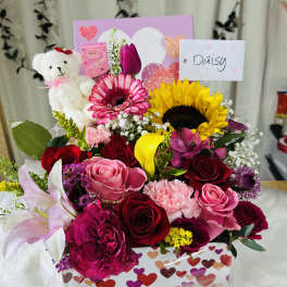 Mixed bouquet with roses, sunflowers, a teddy bear, and chocolates in a heart-patterned box