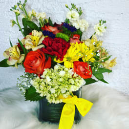 Mixed bouquet in a dark vase with a yellow ribbon
