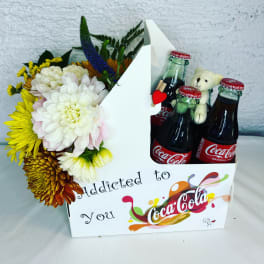Flower arrangement with Coca-Cola bottles and a teddy bear in a gift box