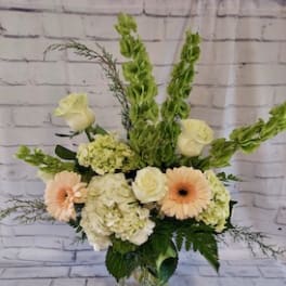Mixed bouquet with pale roses, gerbera daisies, and hydrangeas in a glass vase