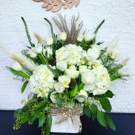 White floral arrangement with tulips and hydrangeas in a wrapped container