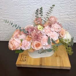 Blush and peach floral arrangement in a white container