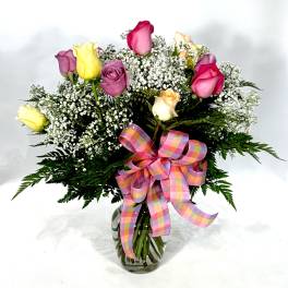 Bouquet of multicolored roses with baby's breath in a glass vase
