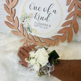 White rose wrist corsage with ribbon on a person's wrist