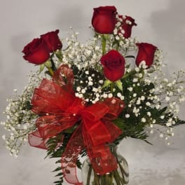 Red roses with baby's breath in a glass vase and red ribbon