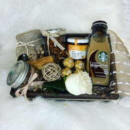 Gift basket with coffee drink, jars, chocolates, and a white rose