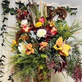 Tall mixed floral arrangement in a clear glass vase with autumn colors