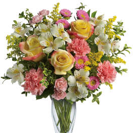 Mixed bouquet of roses, carnations, and white alstroemeria in a glass vase
