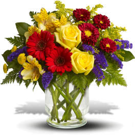 Bouquet of yellow roses, red daisies, and purple filler in a glass vase
