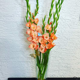 Tall peach gladiolus arrangement in a clear glass vase