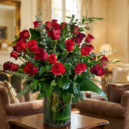 Red roses arranged in a clear glass vase with greenery