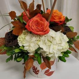 Orange roses and white hydrangeas in a leaf-patterned container