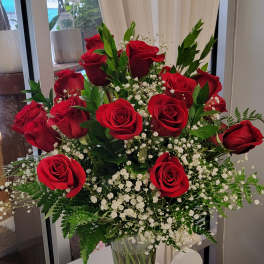Red roses arranged in a clear glass vase with white baby's breath