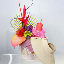 Bright tropical floral arrangement with a woven visor and pink cup