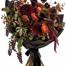 Bouquet of dark burgundy and orange flowers wrapped in black paper