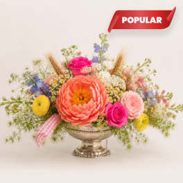 Colorful mixed flower arrangement in a silver pedestal bowl