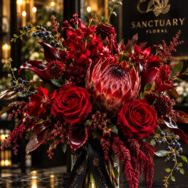 Red floral arrangement in a glass vase with a black ribbon