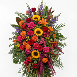 Tall standing floral spray with roses, sunflowers, lilies, and mixed blooms