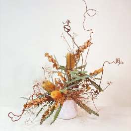 Tall dried floral arrangement in a white vase with curling branches
