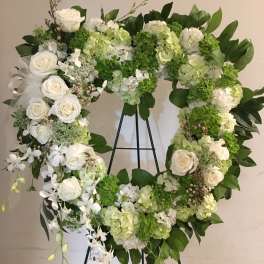 Heart-shaped floral wreath with white roses and green hydrangeas on a stand
