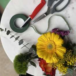 Floral tools and a small bouquet with a yellow gerbera daisy and red rose