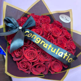 Bouquet of red roses wrapped with a congratulatory ribbon