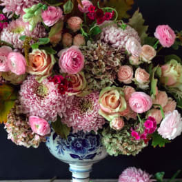 Pink and cream floral arrangement in a blue-and-white pedestal vase