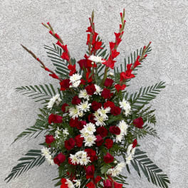 Standing floral spray with red roses and white daisies on a metal easel