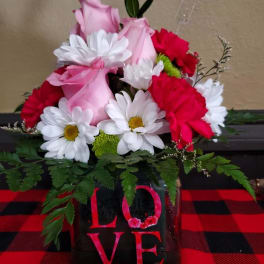 Pink roses and white daisies arranged in a black vase with a LOVE sign