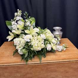 White floral arrangement with lilies and hydrangeas on a wooden table