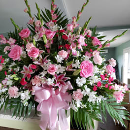 Large pink and white floral arrangement with a pink ribbon bow