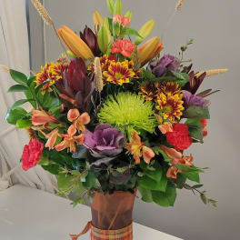 Mixed bouquet in a copper vase with orange, purple, and green flowers