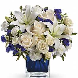 White lilies and roses arranged in a blue glass vase