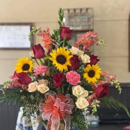 Mixed bouquet of sunflowers, roses, and carnations in a glass vase