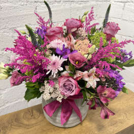 Pink and purple mixed bouquet in a gray vase with a satin ribbon