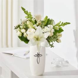 White floral arrangement in a tall vase with a cross emblem