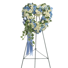 Heart-shaped floral wreath on an easel with blue and white flowers