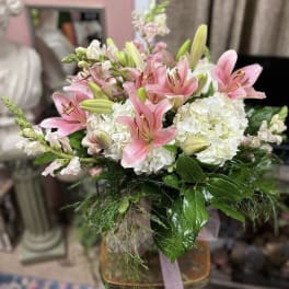 Pink lilies and white hydrangeas arranged in a glass vase