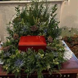 Green funeral wreath around a red urn on a table