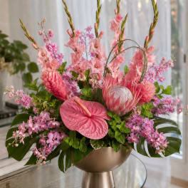 Pink tropical floral arrangement in a gold pedestal vase