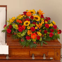 Bright mixed flower spray on a wooden casket